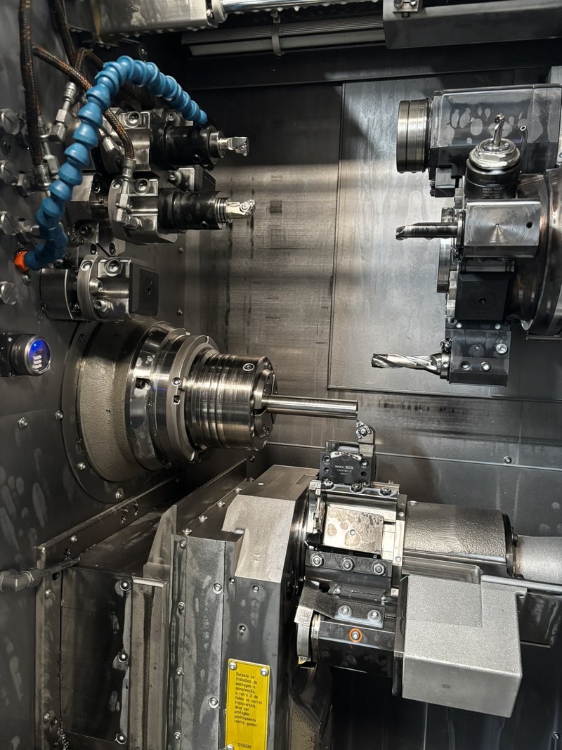 Interior de torno CNC multitarefa com torre de ferramentas acionadas e barra em usinagem